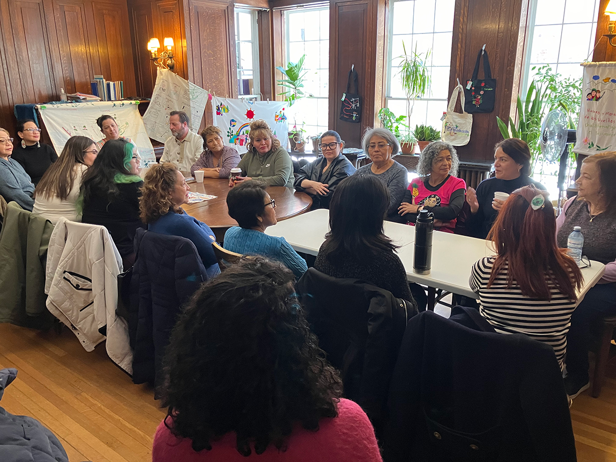 Around twenty people sit in a circle in a warmly lit room, participating in Weaving Absence: A Gathering of Embroiderers. The group listens and exchanges stories about the role of embroidery in preserving collective and personal histories. The workshop, led in Spanish by Teresa Cruz from El Salvador’s Museo de la Imagen y la Palabra (MUPI), explores memory and resilience through the art of stitching.